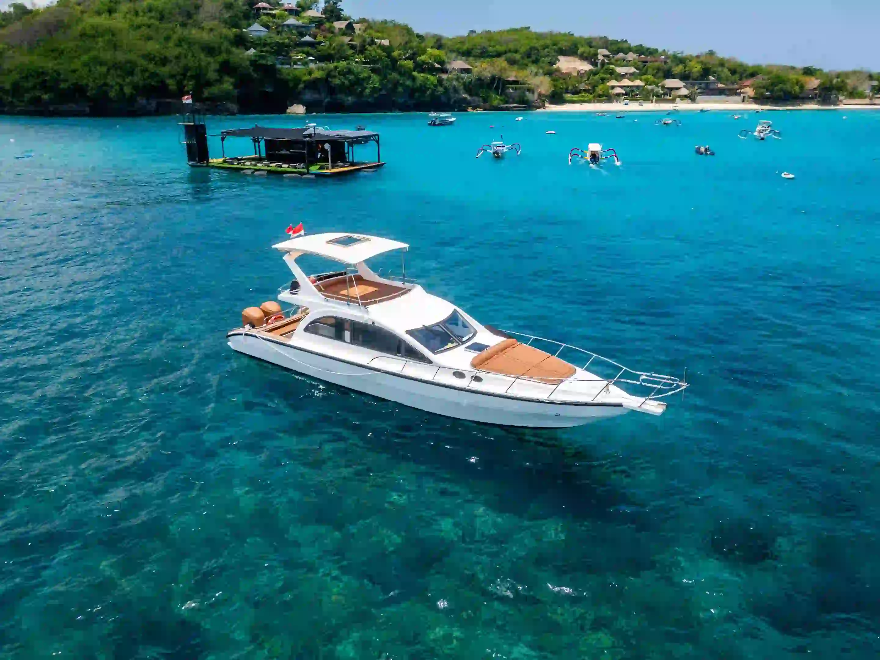 A charter yacht lying at anchor over a turquoise reef