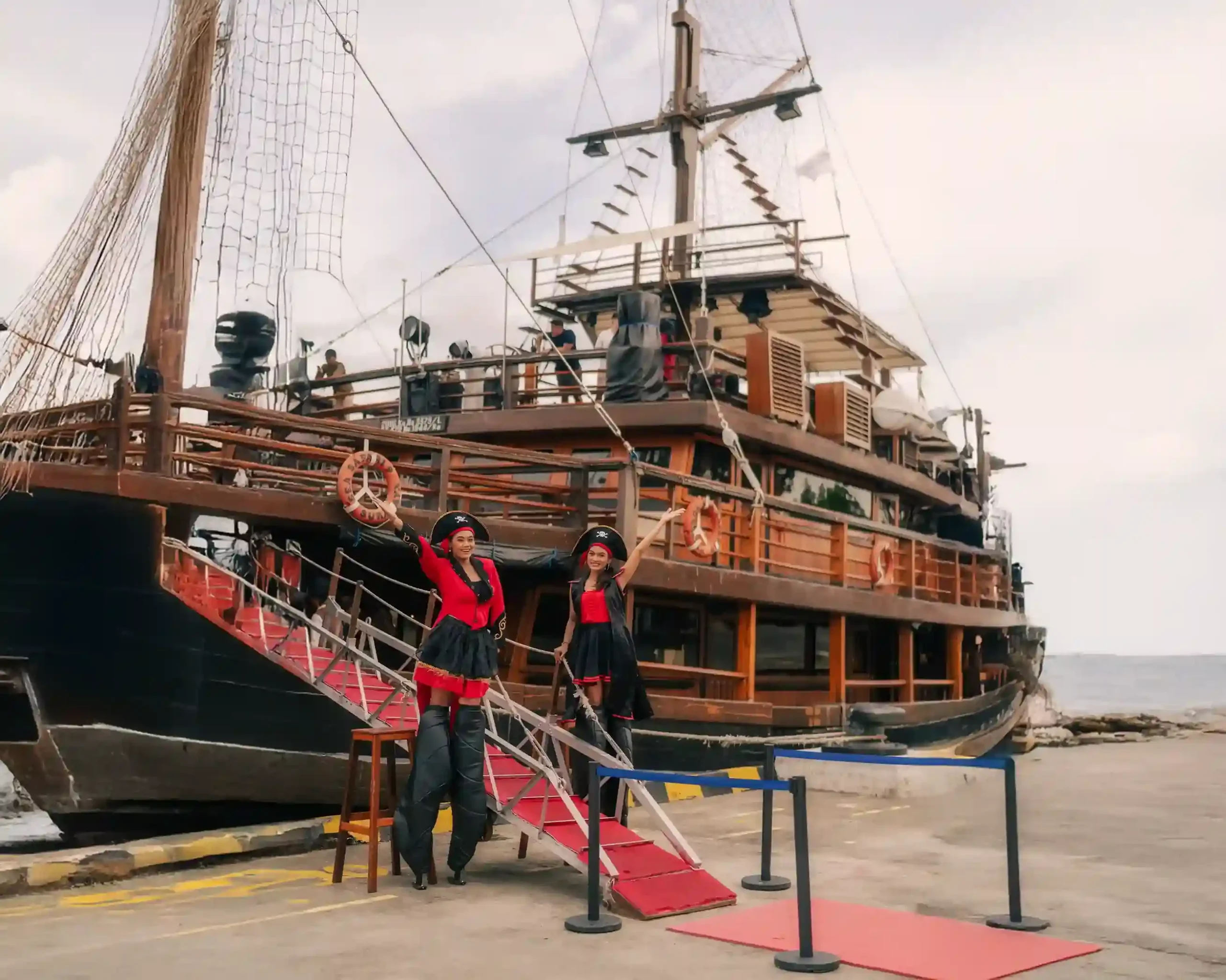 A traditional wooden phinisi alongside, crew on the gangway